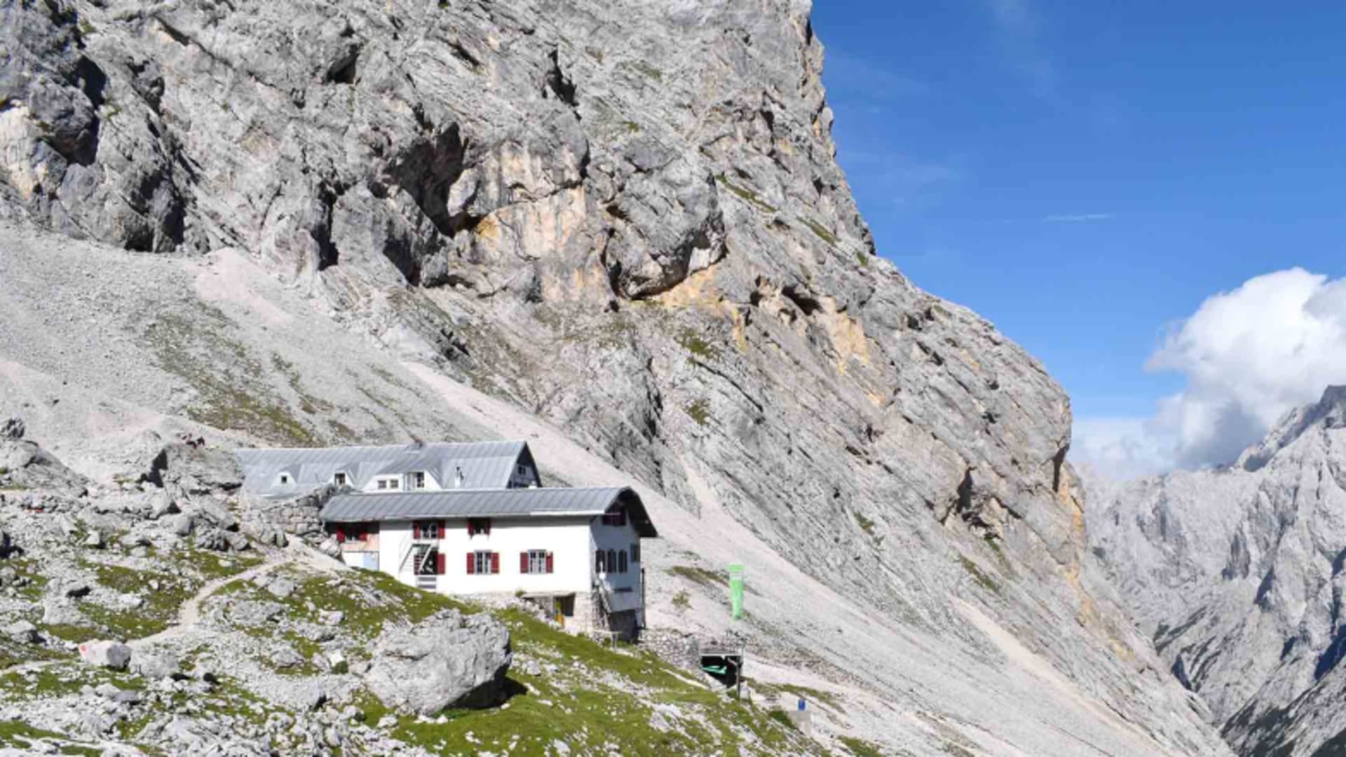 Die Knorrhütte steht vor der steilen Kalksteinwand der Zugspitze im Wettersteingebirge.