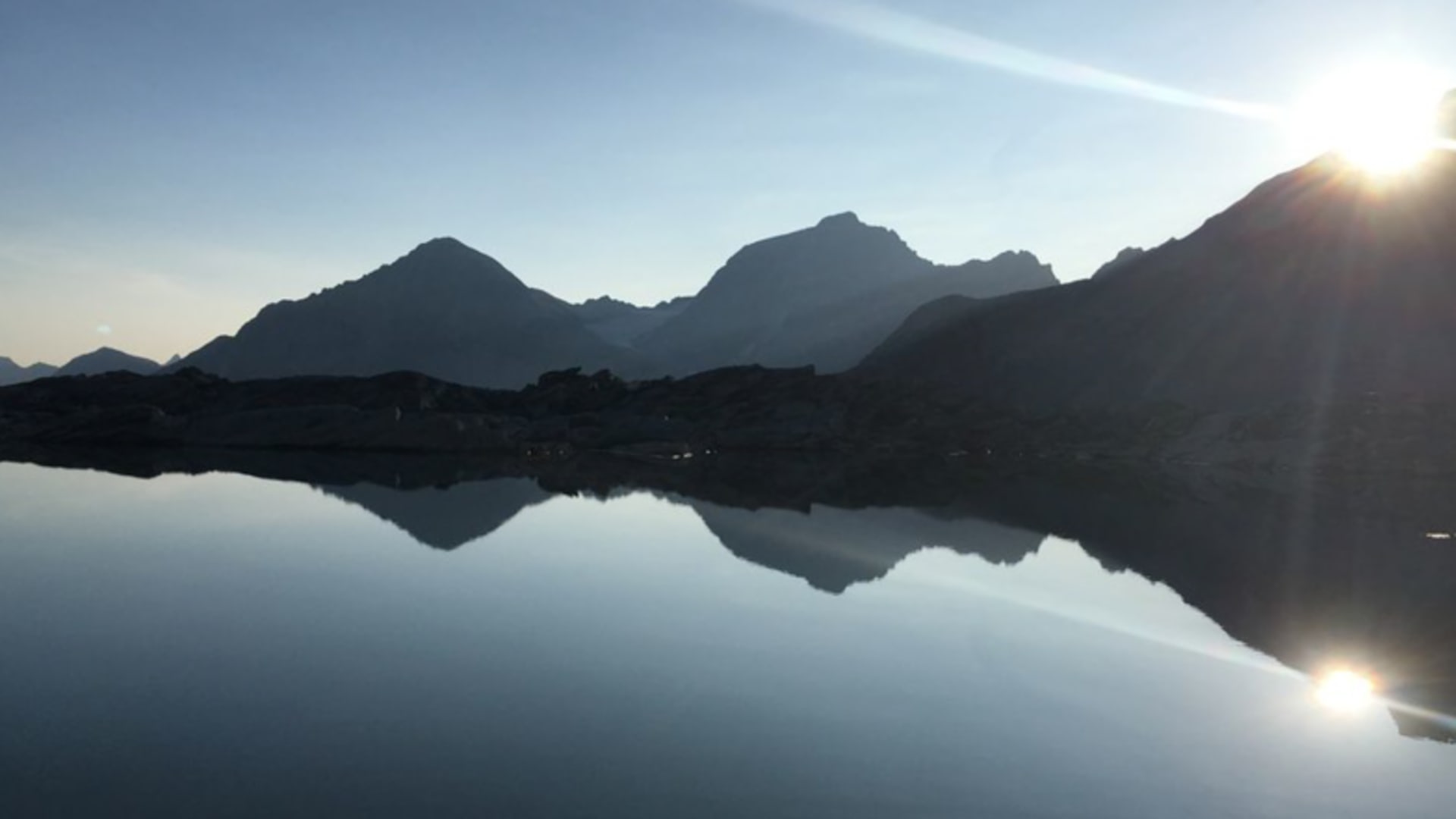 Spiegelglatter Bergsee bei Sonnenaufgang in der Nähe der Chamanna Coaz mit perfekter Bergspiegelung.