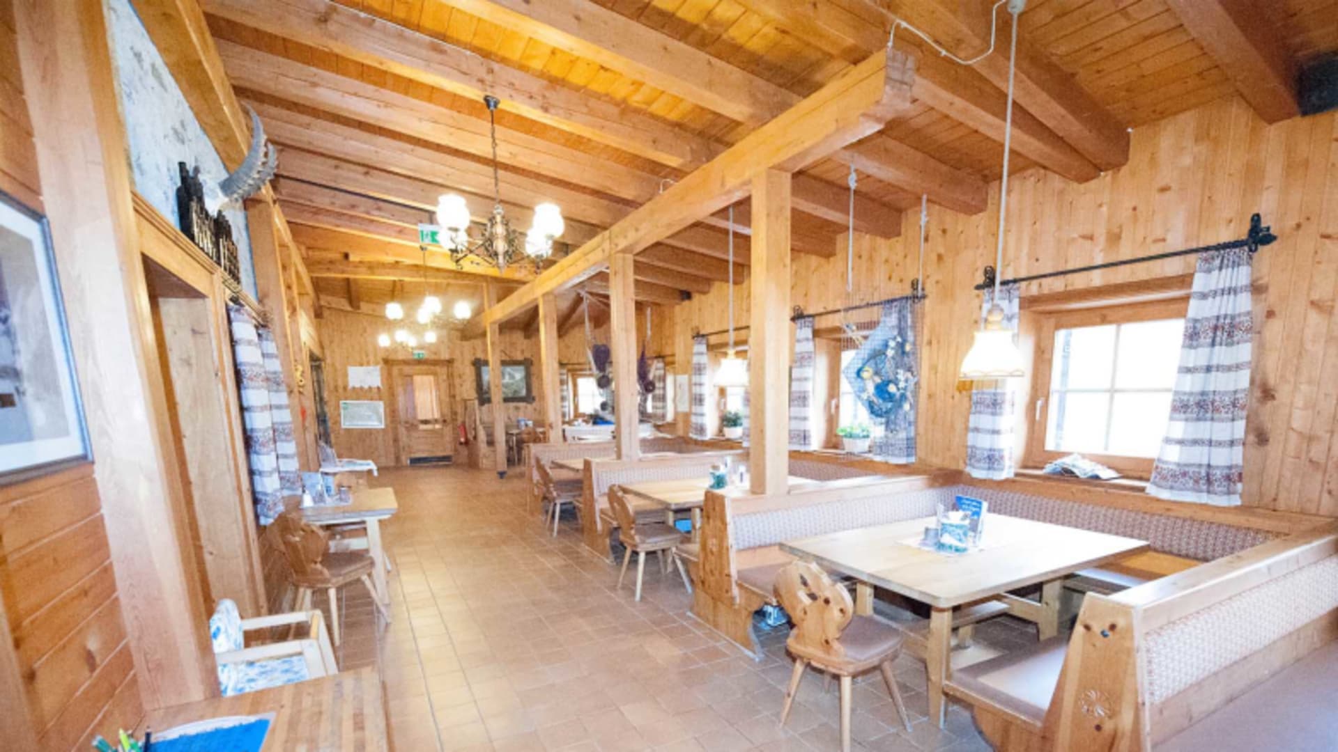 Gastraum der Lucknerhütte mit traditioneller Holzeinrichtung, karierten Kissen und gemütlichen Tischgruppen.