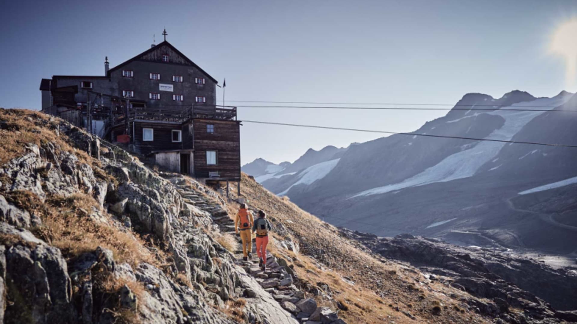 Bergwanderer mit Rucksäcken steigen über Steinweg zur Schutzhütte Schöne Aussicht / Bella Vista auf.
