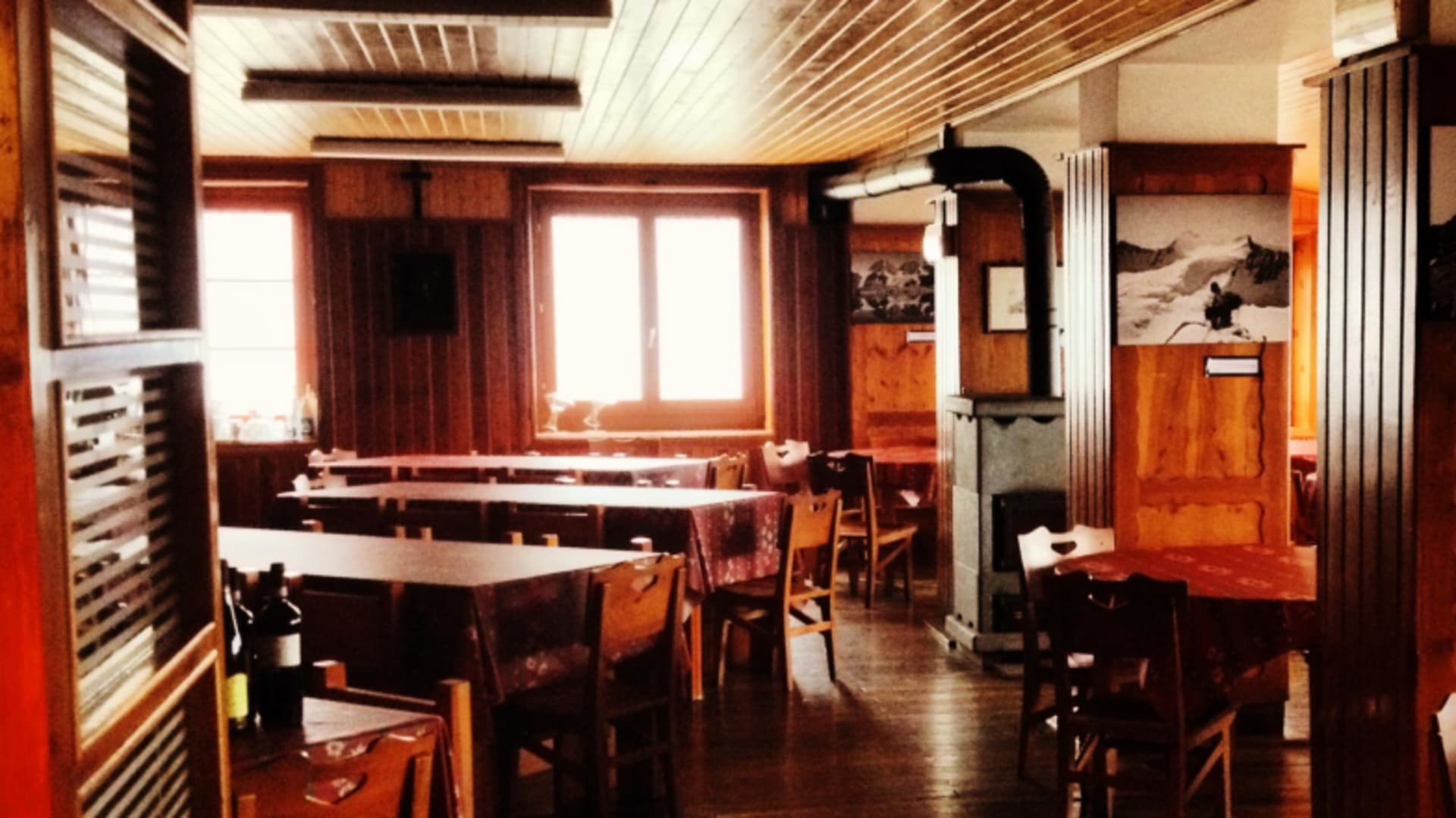 Gemütlicher Gastraum im Rifugio Marinelli Bombardieri mit Holztischen und traditioneller Alpenausstattung.