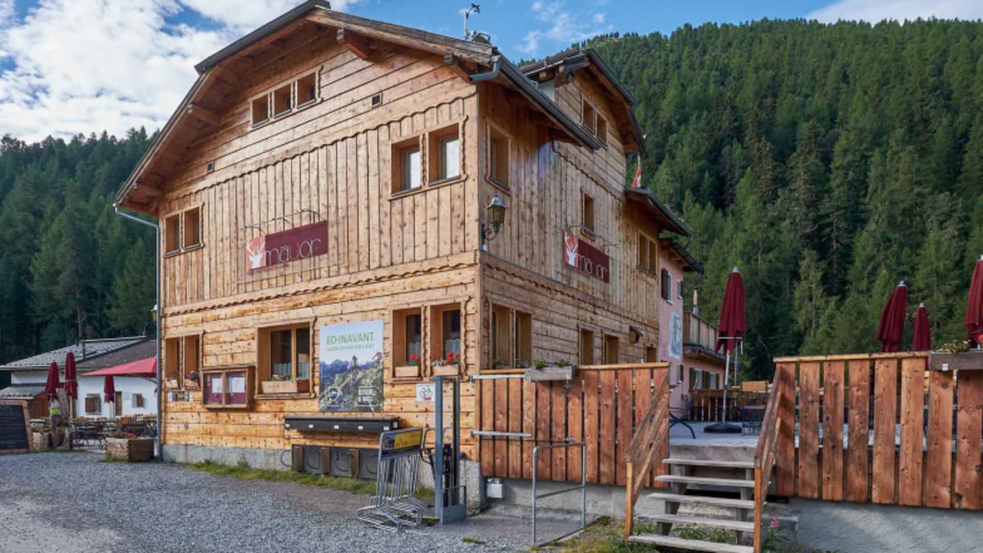 Das Gasthaus Mayor (Schweiz) zeigt sich als dreistöckiges Holzgebäude mit traditioneller Alpenarchitektur und Terrasse.