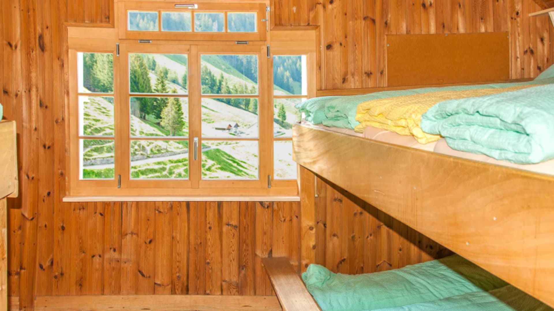 Etagenbetten der Gafadurahütte mit Fenster und Blick auf die Berglandschaft des Rätikon.
