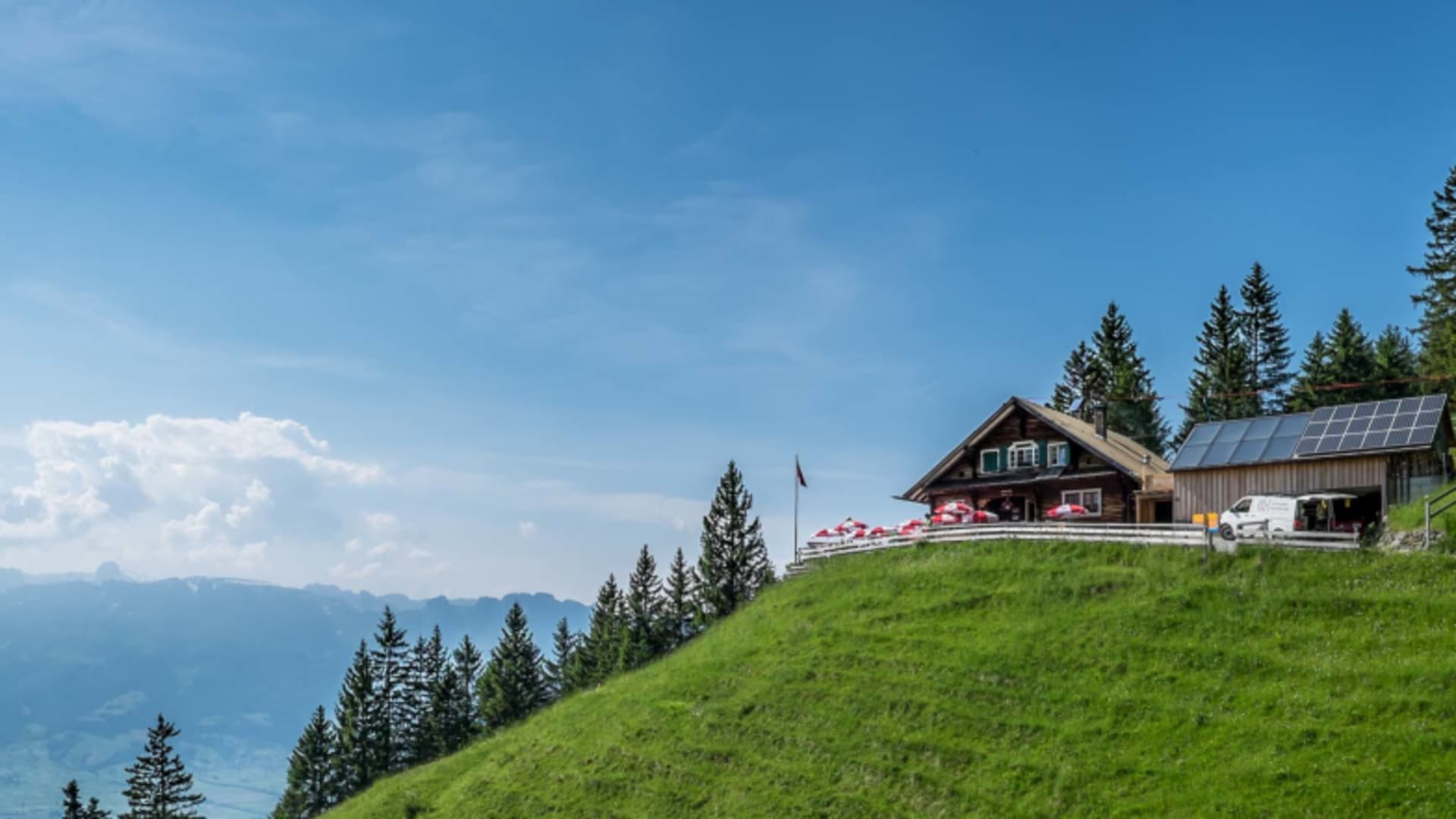 Panoramaaufnahme der Gafadurahütte auf grünem Berghang mit Solarpanels und Talblick ins Rheintal.