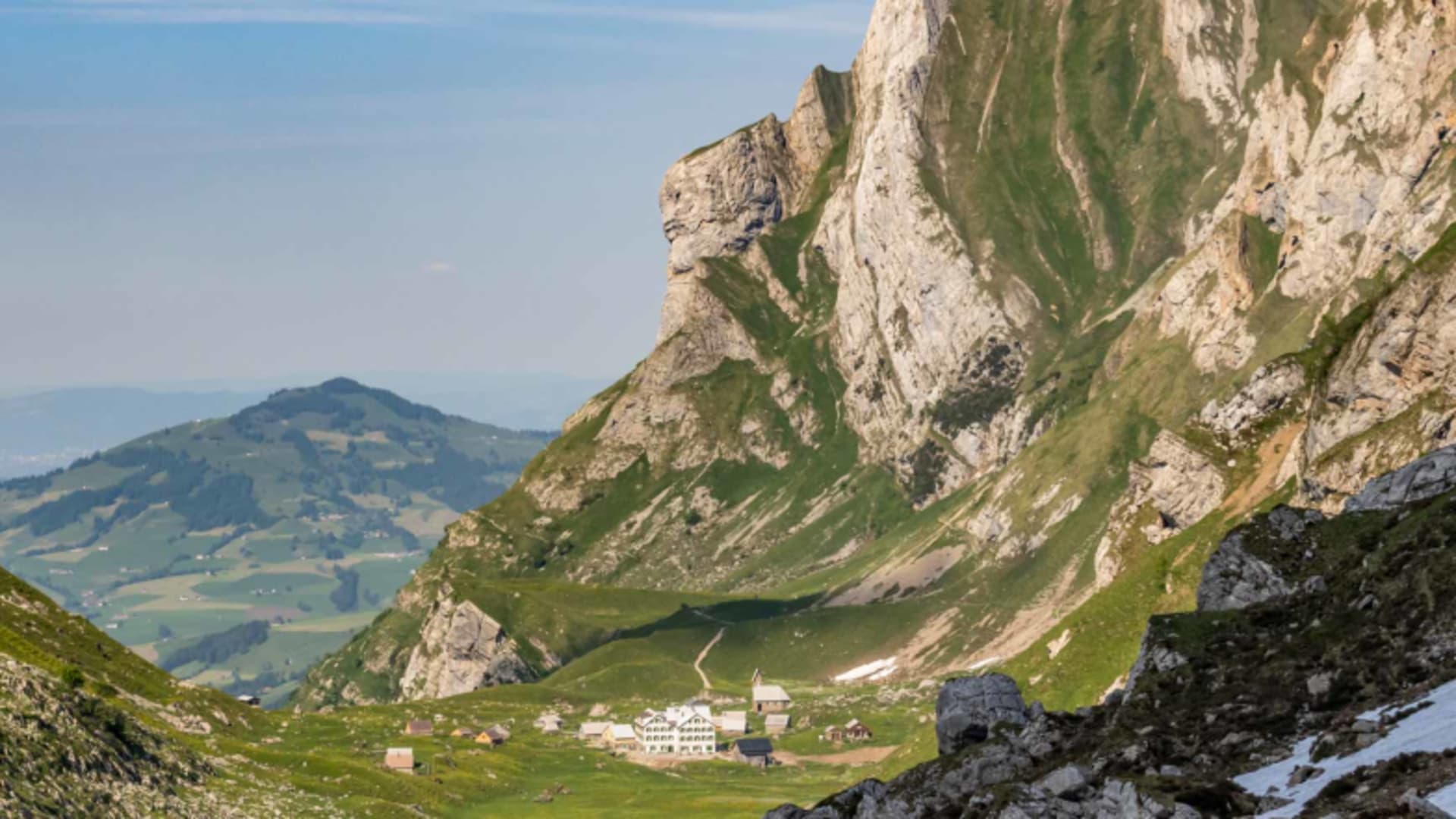 Panoramablick auf das Berggasthaus Meglisalp auf der alpinen Hochebene mit Nebengebäuden und Almhütten.