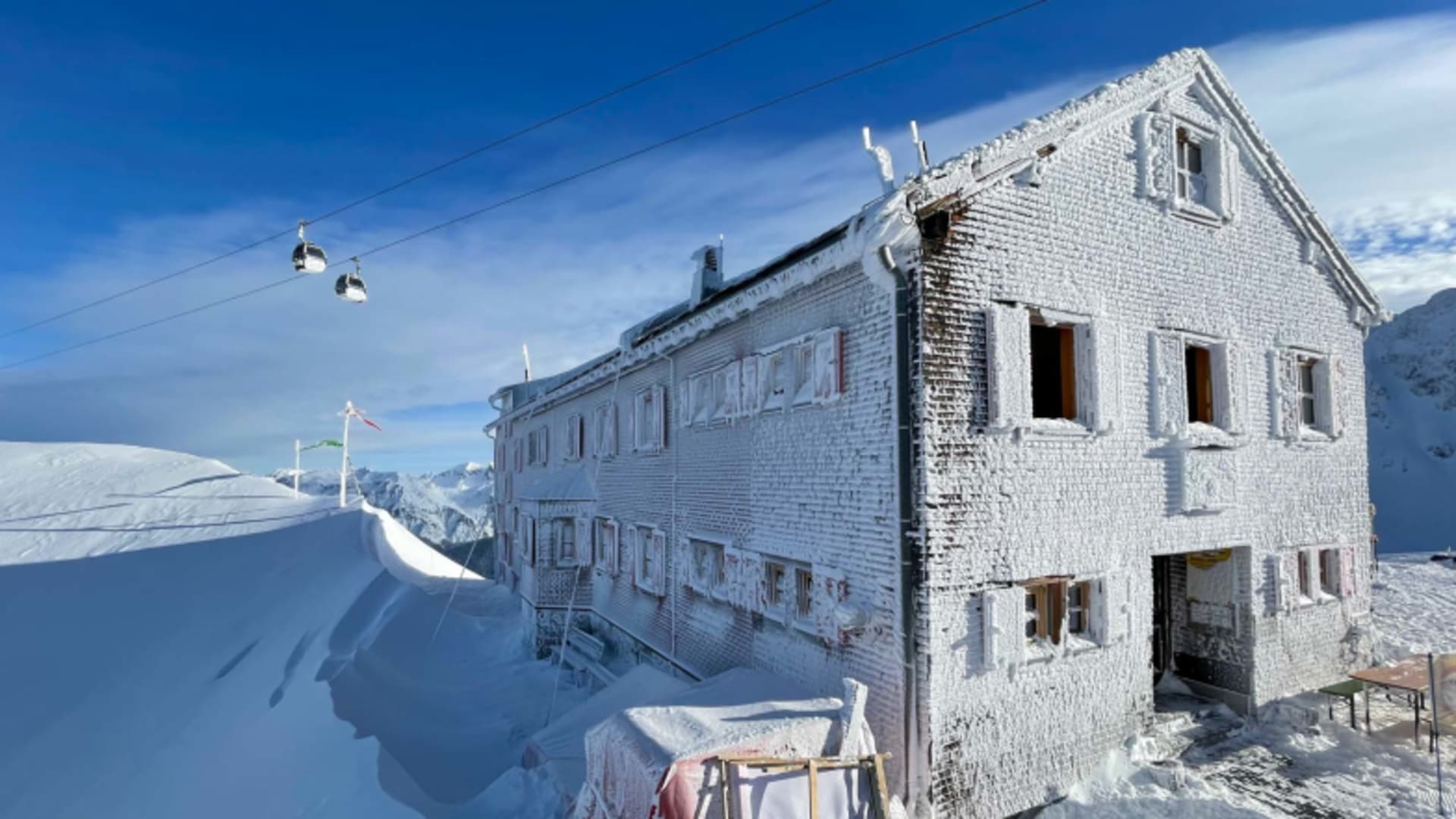 Die Wormser Hütte auf 2.305 m zeigt im Winter eine komplett vereiste Fassade mit meterhohen Schneeverwehungen und warmes Licht in den Fenstern.