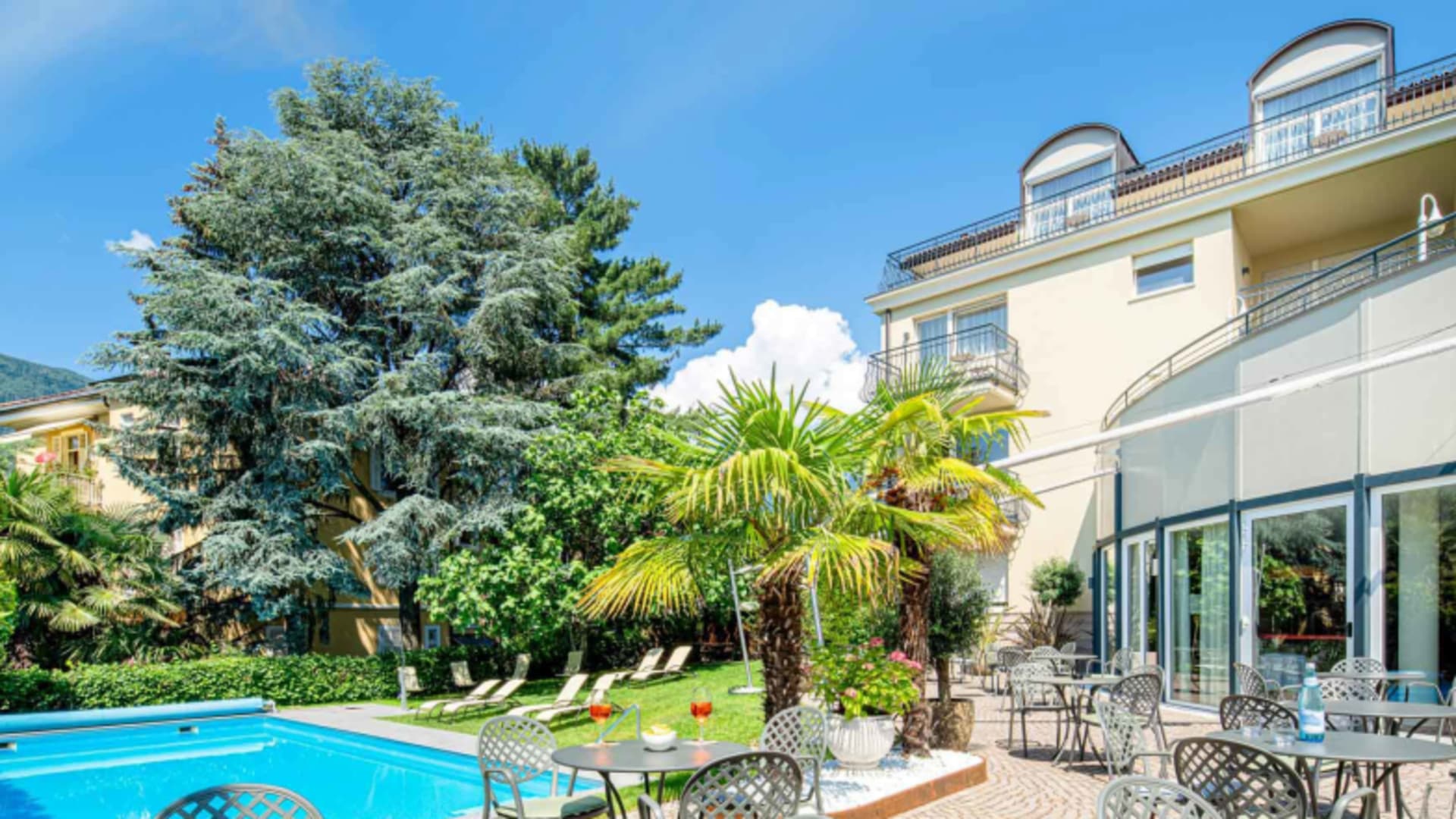 Poolbereich des Hotel Villa Laurus mit Terrasse und Blick auf die bewaldeten Hügel um Meran.