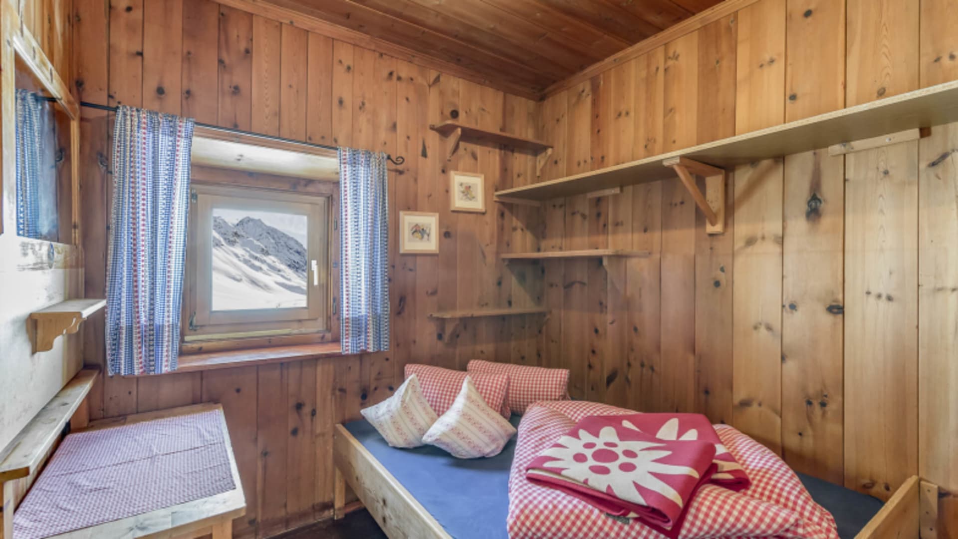 Einzelzimmer in der Amberger Hütte mit Zirbenholz-Verkleidung und rot-weiß karierter Bettwäsche.