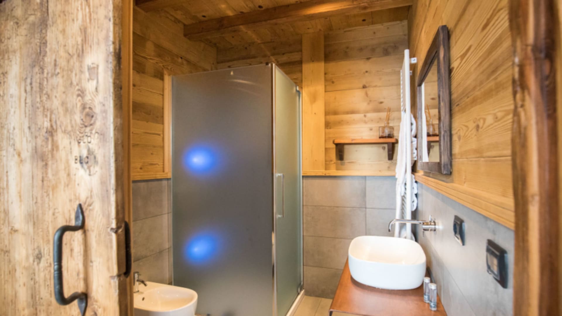 Modernes Badezimmer im Rifugio Torino mit Holzverkleidung, Glasduschkabine und LED-Beleuchtung auf 3375 m Höhe.