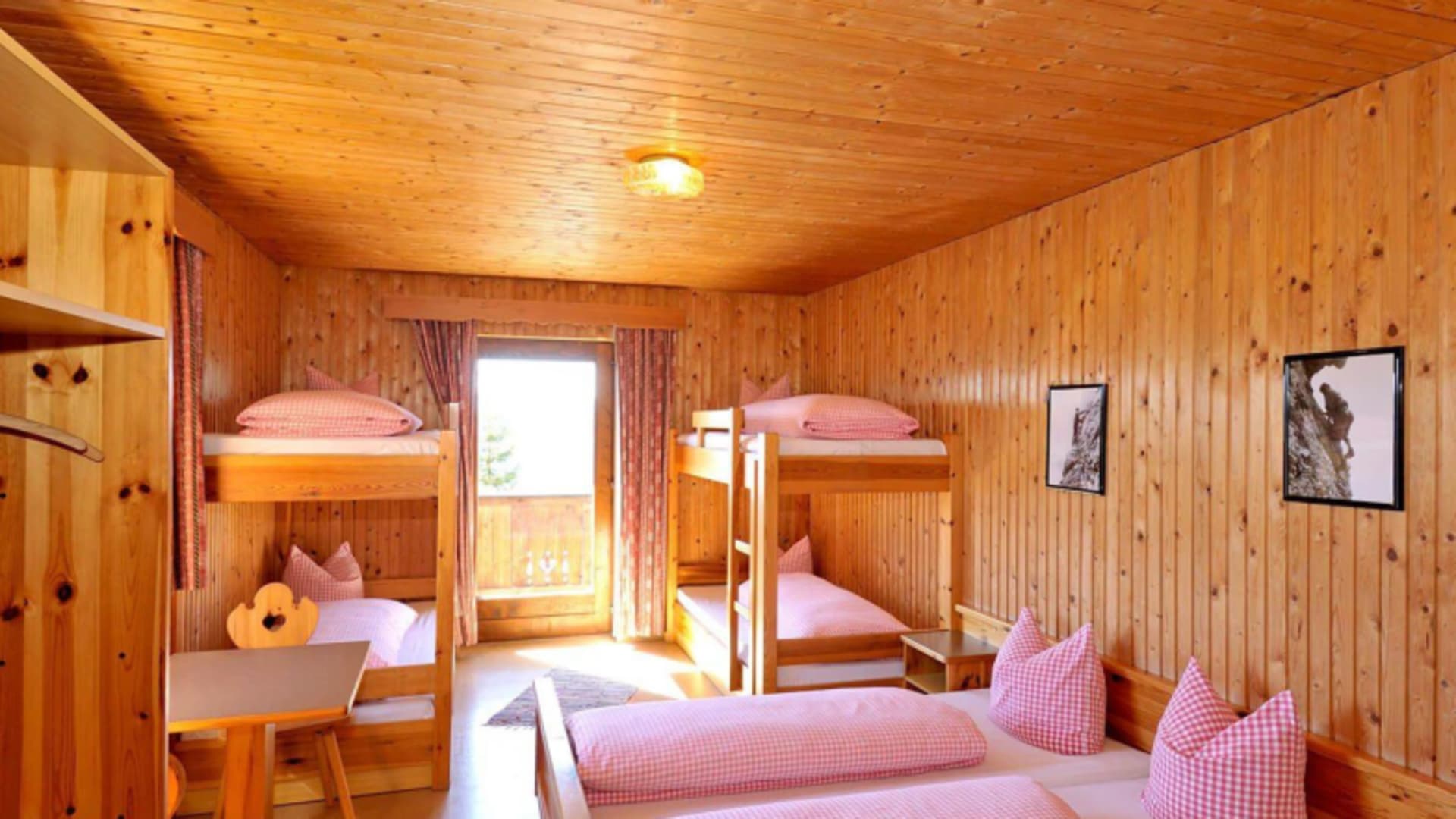 Mehrbettzimmer im Gimpelhaus mit Etagenbetten aus Holz und rot-weiß karierter Bettwäsche in alpiner Hüttenatmosphäre.