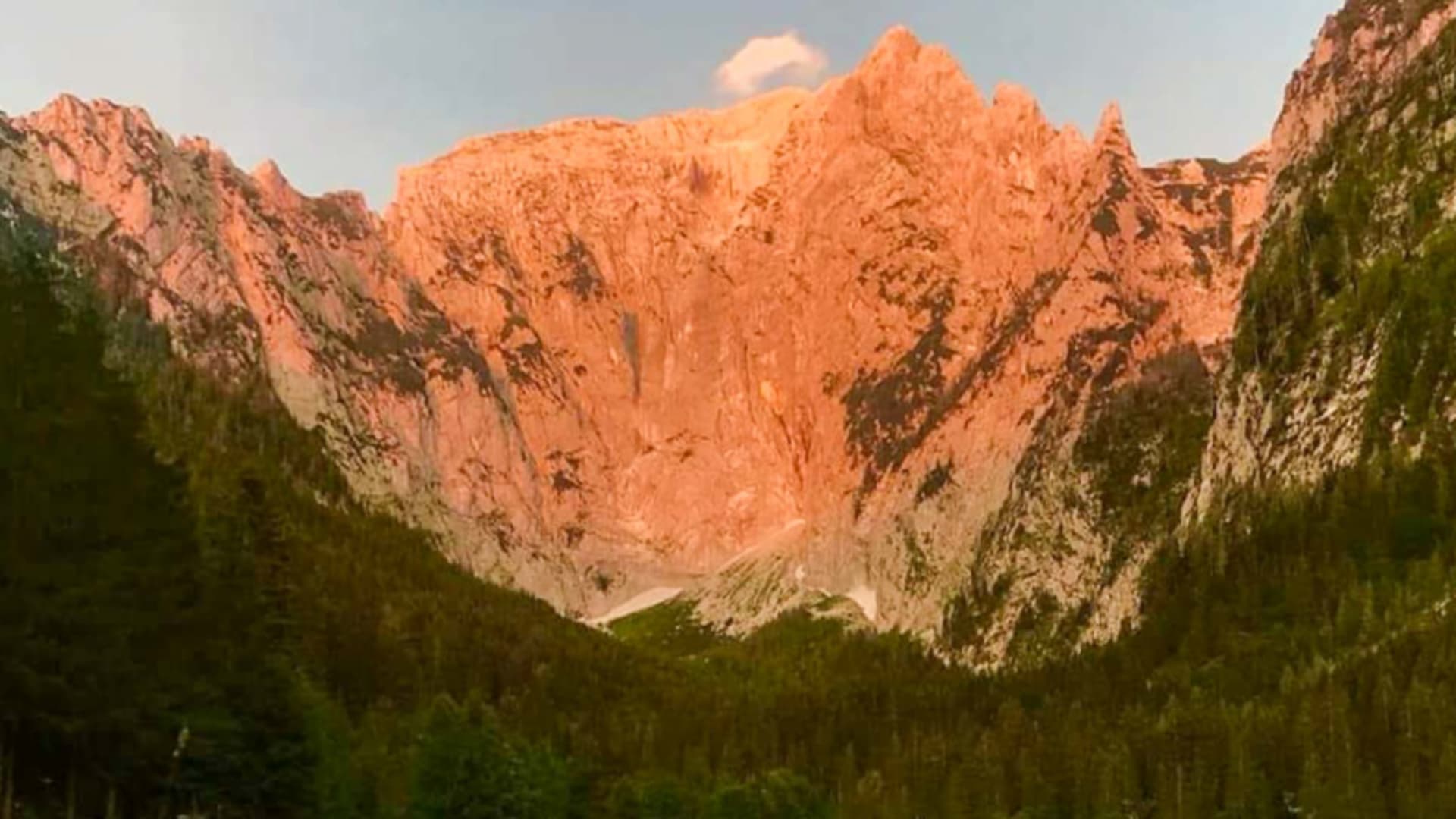 Panoramablick von der Scharitzkehlalm zeigt sonnenbeschienene Felswände und bewaldete Berghänge bei Sonnenuntergang.