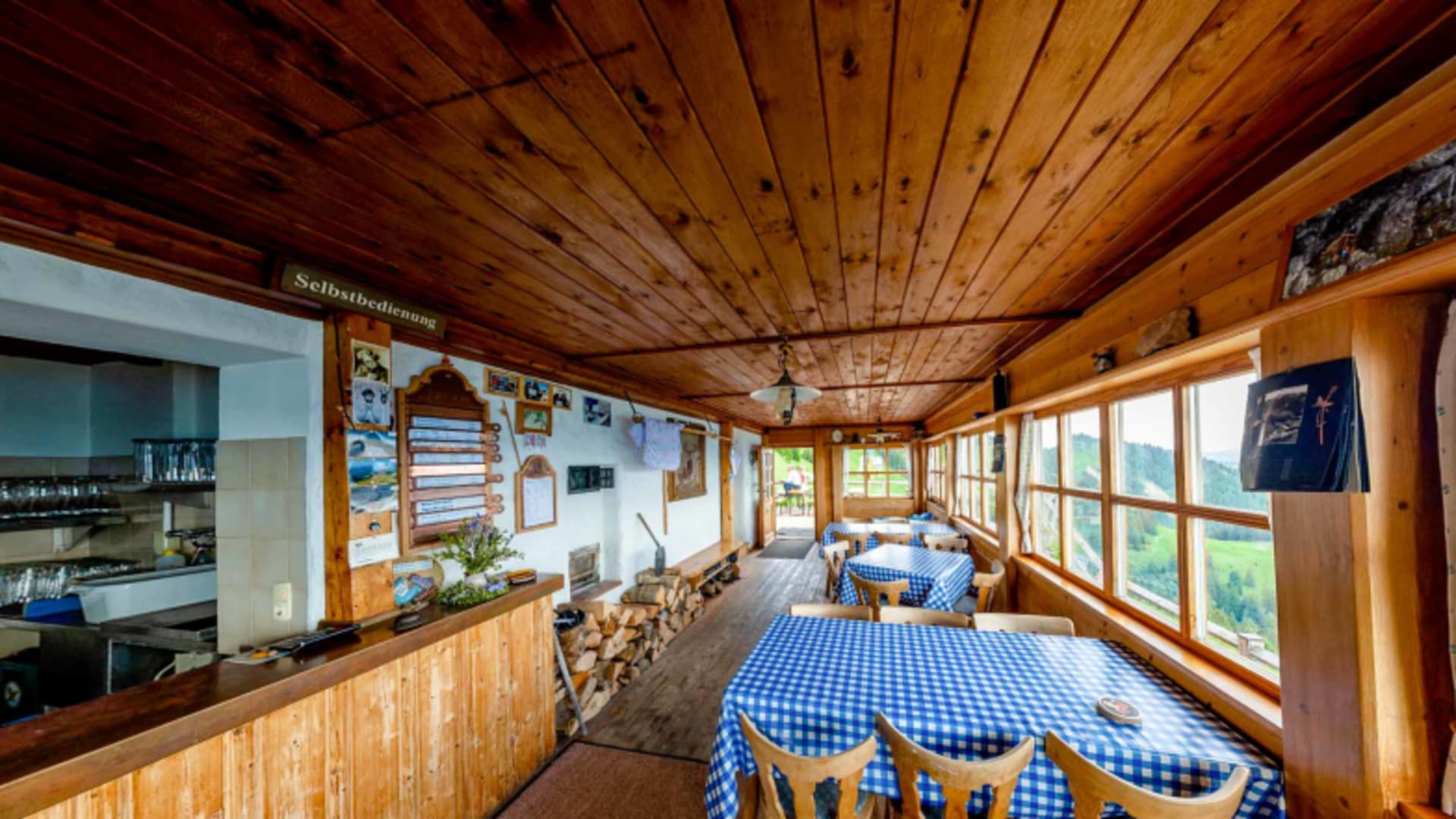 Die Gaststube des Hochgernhaus zeigt traditionelle Holzarchitektur mit blau-weiß karierten Tischdecken und Selbstbedienu