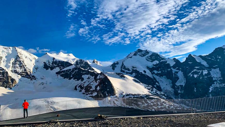 Wanderer auf der Aussichtsplattform des Berghaus Diavolezza mit Blick auf schneebedeckte Berggipfel.