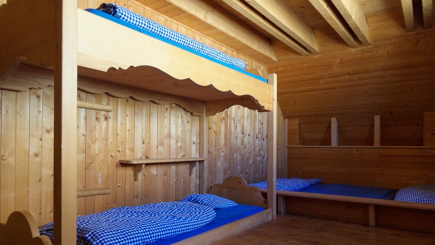 Traditionelle Holzbetten der Cabane du Trient in geschnitzter Alkove mit blau-weiß karierten Bettwäschen.