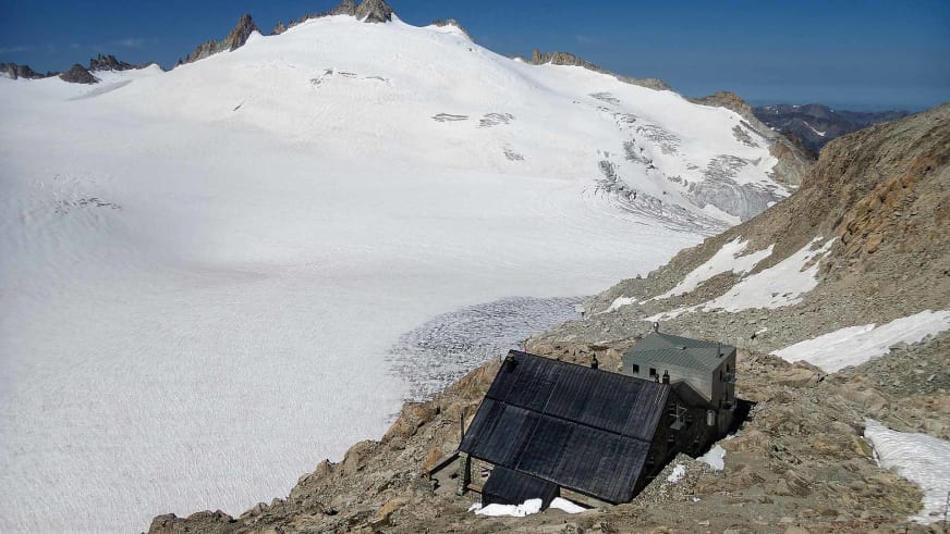 Panorama der Cabane du Trient auf Felsgrat mit großem Gletscher und steilen Felswänden im Hintergrund.