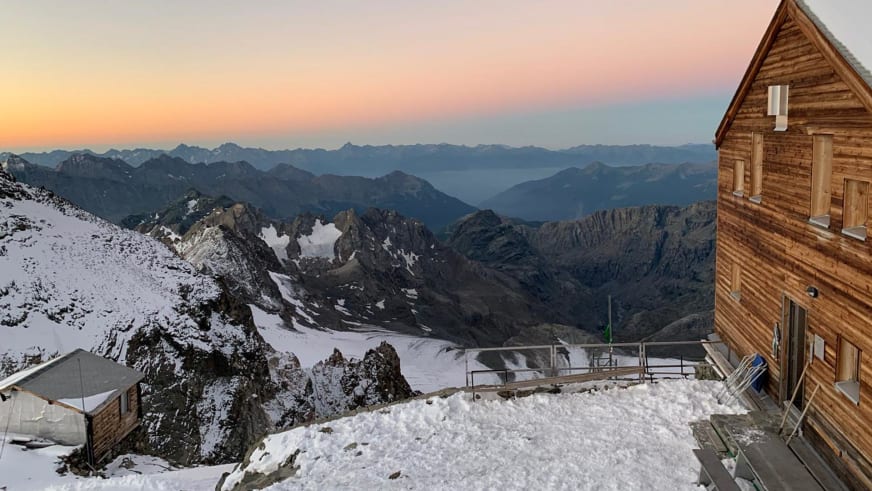 Panoramablick auf die Marco e Rosa Hütte mit schneebedeckten Gebäuden und weitem Ausblick über die Bergketten der Bernin