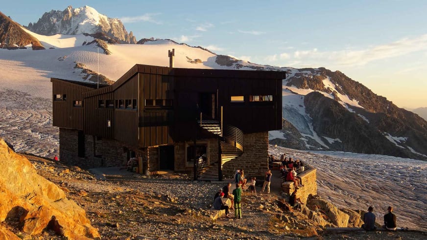 Bergsteiger versammeln sich vor dem Refuge Albert 1er auf 2.706 m im Mont-Blanc-Massiv bei goldenem Abendlicht.