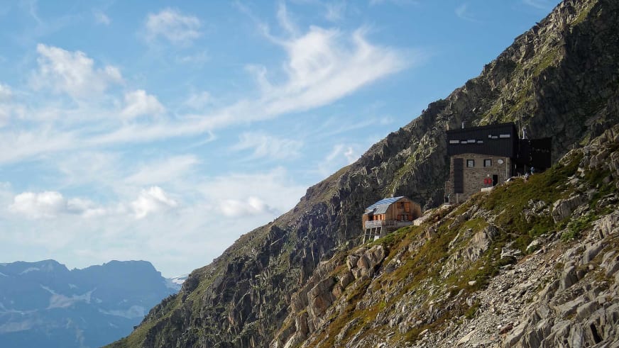 Das Refuge Albert 1er besteht aus mehreren Gebäuden am steilen Felshang mit Solarpaneelen auf dem Dach.