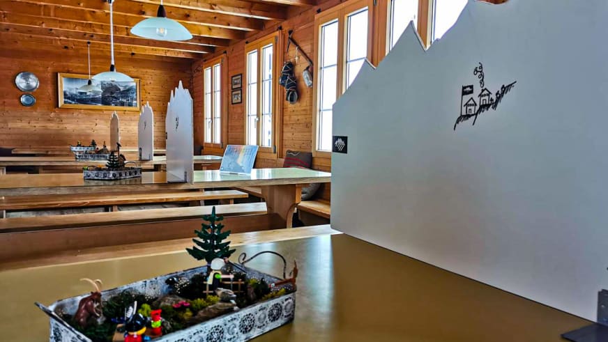 Traditioneller Gastraum der Mischabelhütte mit Holztischen, Bänken und warmer Hüttenatmosphäre aus Holz.