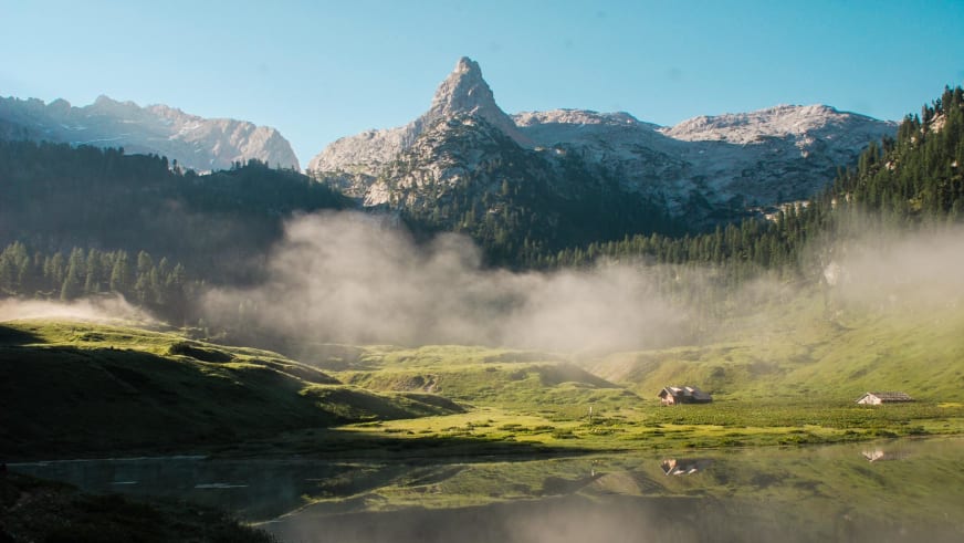 Panoramablick über den Funtensee mit dem Kärlingerhaus und pyramidenförmigem Felsgipfel in der Almlandschaft.