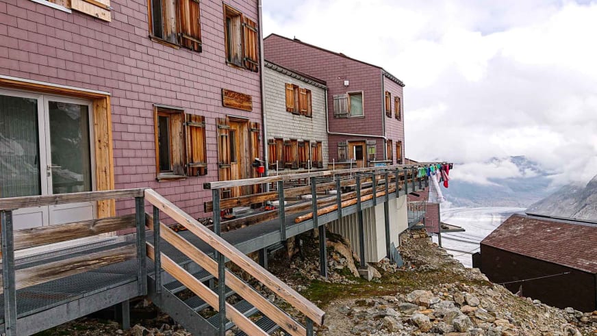 Außenansicht der Konkordiahütte mit violett-grauer Holzfassade und großer Terrasse.
