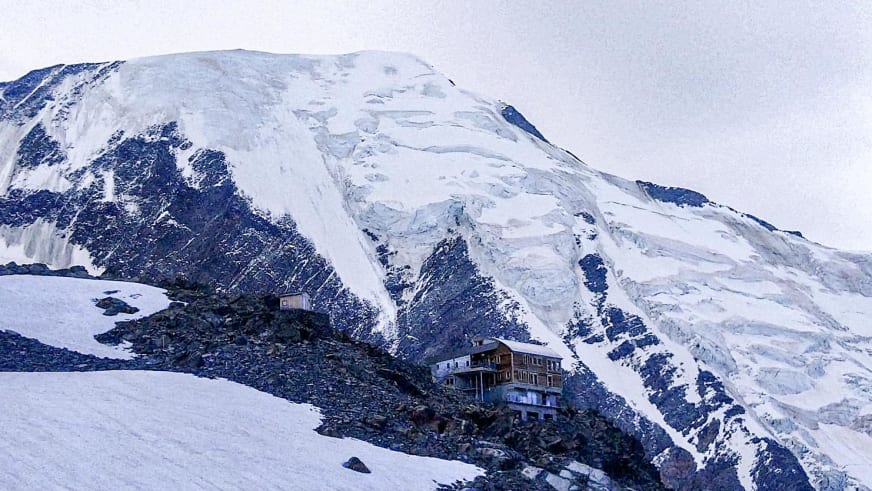 Das Refuge de Tête-Rousse steht auf einem Felshang zwischen Schneeflächen und Gletscherfeldern im Mont-Blanc-Massiv.