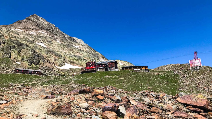 Panoramaaufnahme der Vernagthütte mit Nebengebäuden und Seilbahnstation in hochalpiner Landschaft.
