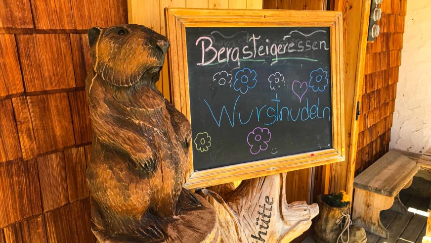 Geschnitzte Holzfigur eines Murmeltiers neben einer Kreidetafel in der Vernagthütte.