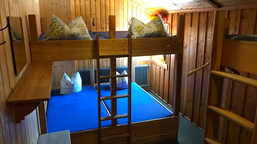 Mehrbettzimmer der Vernagthütte mit Etagenbetten aus Holz und blauen Matratzen.