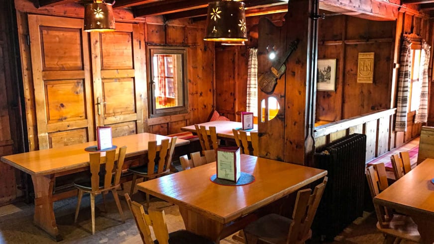 Gastraum der Vernagthütte mit Holztischen und -stühlen in traditioneller Alpenarchitektur.