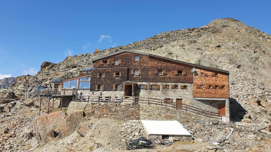 Die Similaunhütte mit großer Terrasse und Panoramafenstern bei klarem Himmel und perfekten Bedingungen.