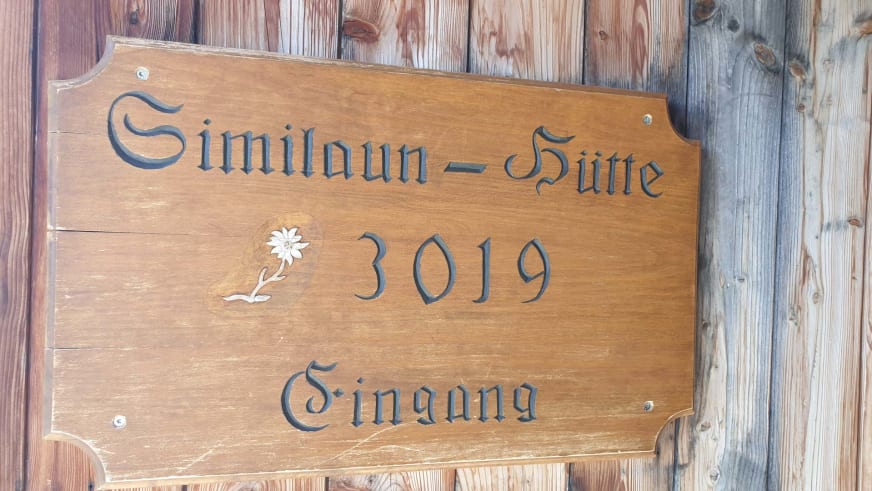 Holzschild der Similaunhütte mit eingeschnitzter Aufschrift '3019 Eingang' und Edelweiß-Symbol.