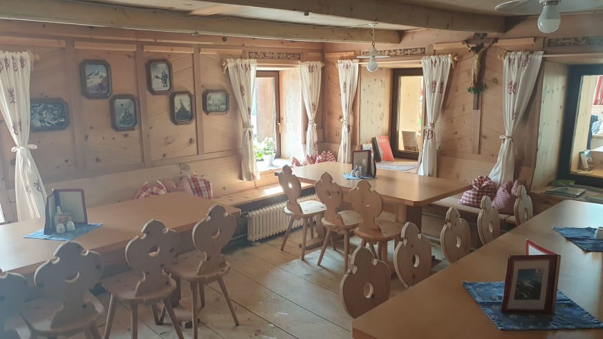Gastraum der Similaunhütte mit geschnitzten Holzstühlen, Bergbildern und traditioneller Alpenausstattung.