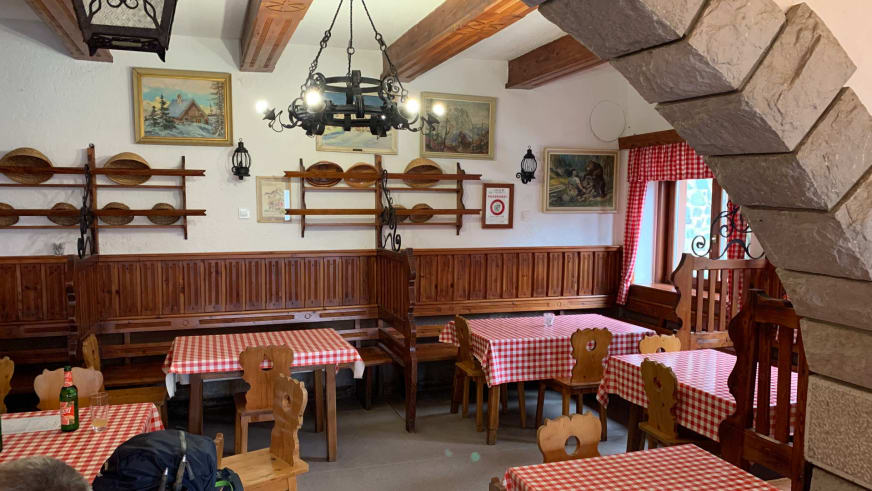 Traditioneller Gastraum im Tičarjev dom na Vršiču mit geschnitzten Holzstühlen und Kronleuchter.