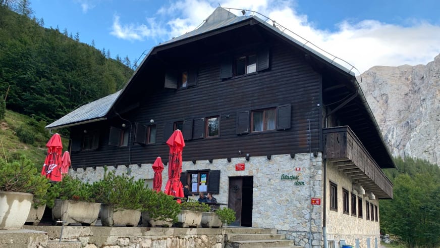Zweistöckige Berghütte Tičarjev dom na Vršiču mit Holzfassade und Steinuntergeschoss in den Julischen Alpen.