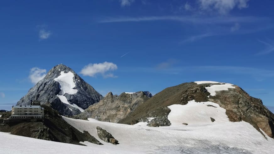Fernblick zeigt das Rifugio Casati am Bildrand vor schneebedeckten Gipfeln und zusammenhängenden Gletscherflächen.