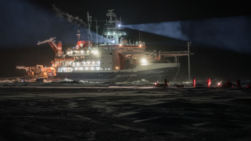 Das beleuchtete Forschungsschiff Polarstern liegt nachts im Packeis, während Bergführer Hans Honold die Mosaic Expedition begleitet.