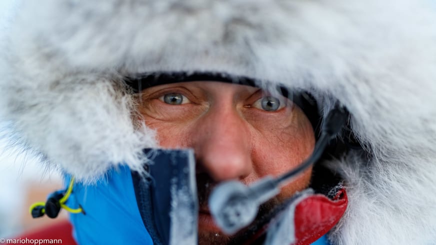 Nahaufnahme von Bergführer Hans Honold mit weißer Pelzkapuze voller Eiskristalle bei extremen Temperaturen in der Arktis.