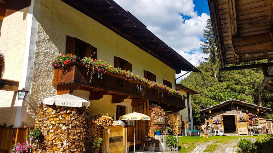 Gesamtansicht vom Alpengasthof Bad Kalkstein Innervillgraten mit gelbem Haupthaus und Sonnenschirmen.