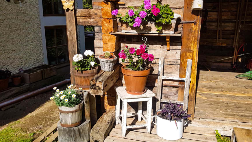 Holzterrasse am Alpengasthof Bad Kalkstein Innervillgraten mit Sommerblumen und Holzdekoration.