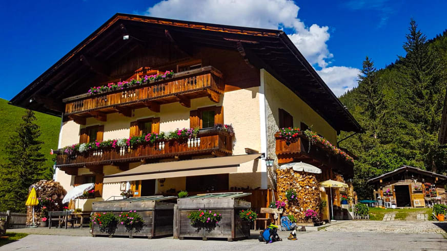 Außenansicht vom Alpengasthof Bad Kalkstein Innervillgraten mit Holzbalkonen und Wanderrucksäcken.