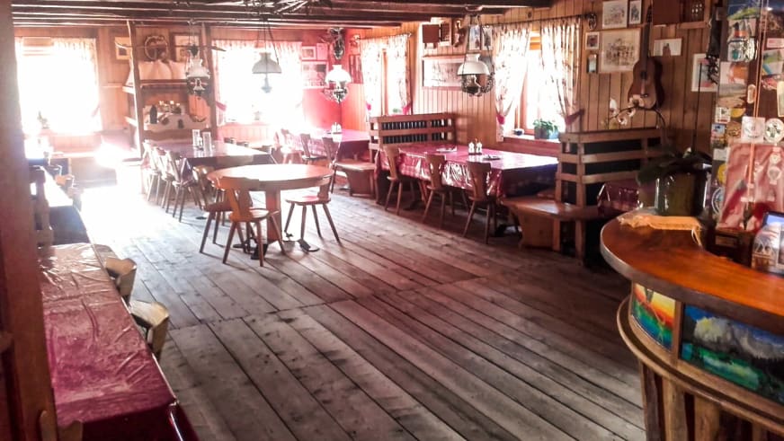 Gemütlicher Gastraum der Faneshütte (Rifugio Fanes) mit Holztischen und rot-weiß karierten Tischdecken.