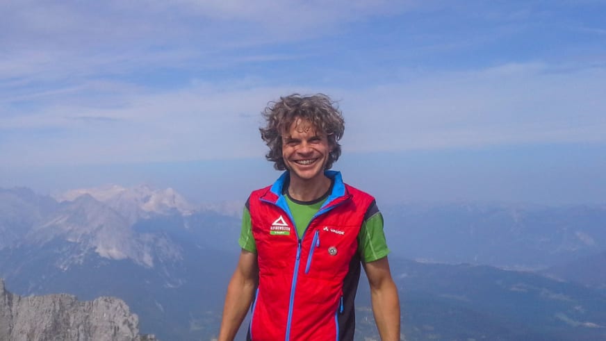 Am Höllental-Klettersteig zur Zugspitze lächelt Bergführer Michael Hornsteiner vor weitem Bergpanorama mit Kalkfelsen.
