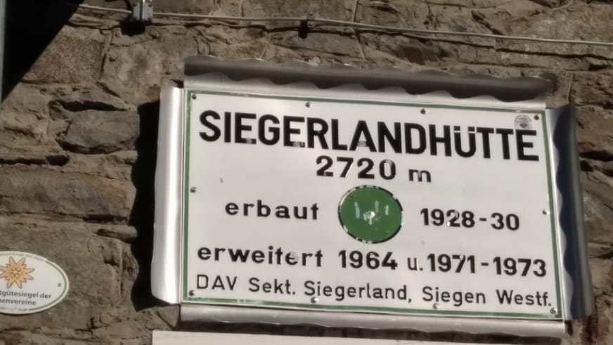 Weißes Schild der Siegerlandhütte zeigt Höhe 2.720 m und Baugeschichte der DAV-Hütte.