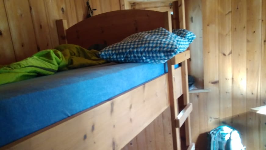 Stockbett der Siegerlandhütte mit blauem Spannbettlaken und Schlafsack im Holz-Schlafraum.