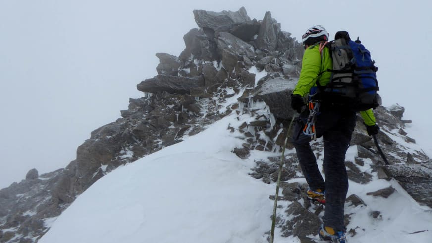 Bergführer Simon Kraus führt eine Hochtour auf schneebedecktem Felsgrat in dichtem Nebel mit zweiter Person.