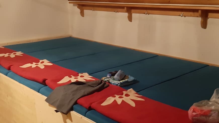 Übernachtungsraum der Gaudeamushütte mit Doppelbett und sichtbaren Holzbalken an der Decke.