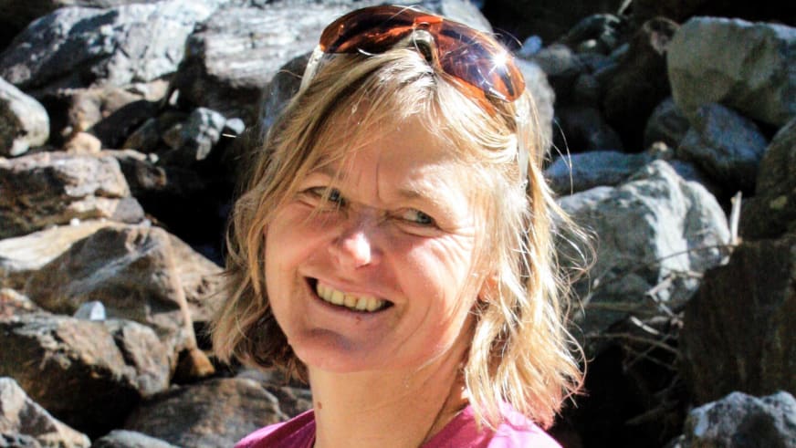Nahaufnahme von Bergwanderführerin Isolde Fink im pinken Funktionsshirt mit Sonnenbrille vor Geröllhalde.
