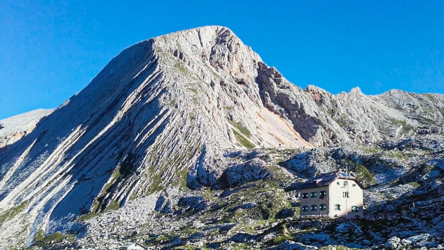 Panoramablick auf die Seekofelhütte (Rifugio Biella) zwischen Geröllfeldern mit steilen Kalksteinfelsen der Dolomiten da
