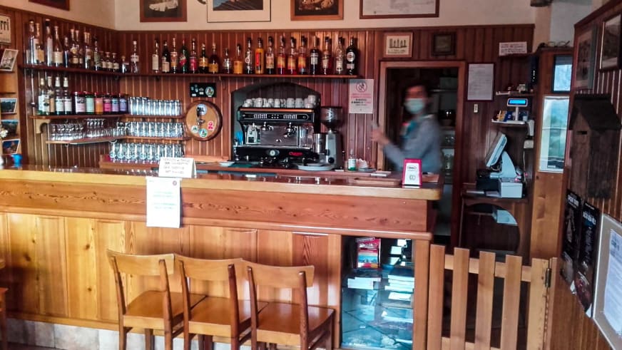 Traditioneller Holztresen im Rifugio Cinque Torri mit Spirituosensammlung, Espressomaschine und rustikaler Hütteneinrich